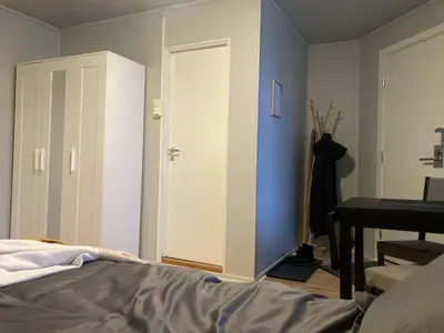 a bedroom with a bed and a white door at Sentrumsnær studioleilighet! in Trondheim