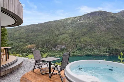 a hot tub on a deck with a table and chairs at Sogndal Fjordpanorama- The Panorama View in Kaupanger