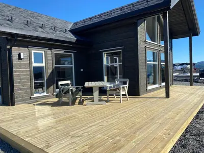 a house with a wooden deck with a table and chairs at Nydelig hytte ved Voss Ski og Tursenter in Giljane