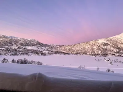 a snow covered field with a mountain in the background at Heimro in Torvetjørn