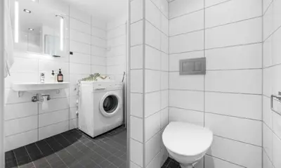 a white bathroom with a washing machine and a toilet at Nydelig leilighet på Nordnes! in Bergen