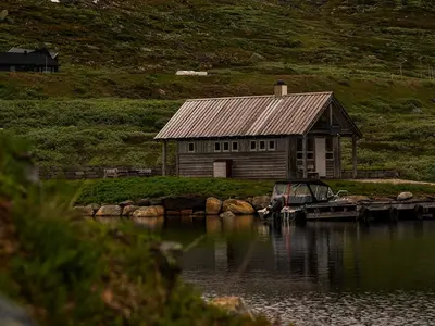 a cabin on the shore of a body of water at Halne Fjellstugu in Maurset