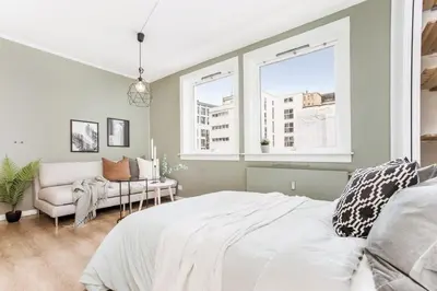 a bedroom with a bed and a couch and windows at Charming studio apartment in Bergen