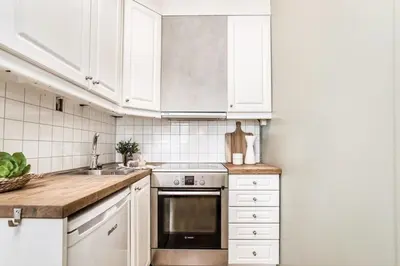 a kitchen with white cabinets and a sink and a stove at Charming studio apartment in Bergen
