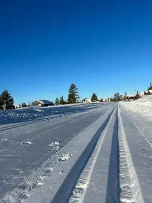 an empty road covered in snow with a blue sky at Eventyrtunet in idyllic Tuddal in Hjartdal