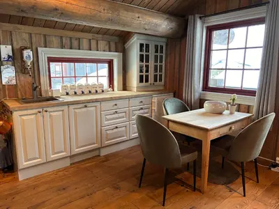 a kitchen with a table and chairs and a sink at Eventyrtunet in idyllic Tuddal in Hjartdal