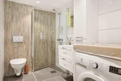 a bathroom with a toilet and a shower and a washing machine at Dinbnb Homes I Bergen's #1 BNB I Jacuzzi & Fireplace & Balcony in Bergen
