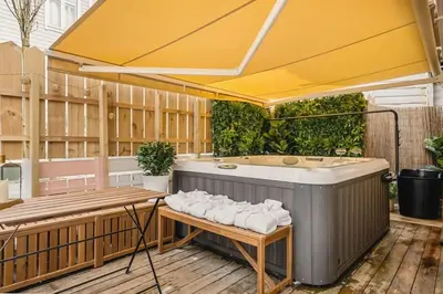 an outdoor hot tub with a table and an umbrella at Dinbnb Homes I Bergen's #1 BNB I Jacuzzi & Fireplace & Balcony in Bergen