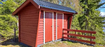 a red shed with a black roof and a fence at Vesletun in Balestrand