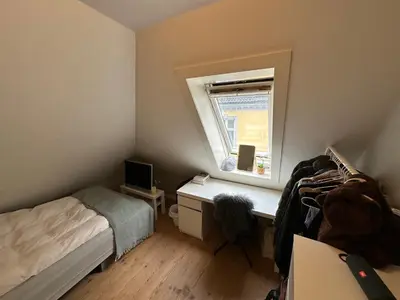 a bedroom with a bed and a desk and a window at Sjarmerende bolig like ved togstasjonen in Bergen