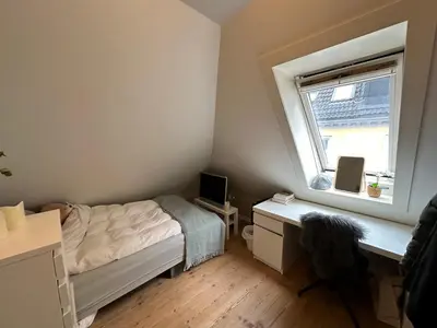 a bedroom with a bed and a desk and a window at Sjarmerende bolig like ved togstasjonen in Bergen