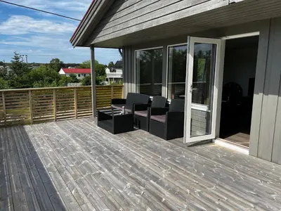 a deck with chairs and tables on a house at Feriehus nær sjøen på Kvenvær in Hitra