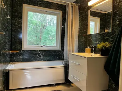 a bathroom with a window and a tub and a sink at Feriehus nær sjøen på Kvenvær in Hitra