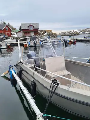 a white boat tied to a dock in the water at Feriehus nær sjøen på Kvenvær in Hitra