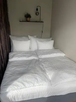 a large bed with white sheets and pillows at Modern apartment ONLY 5 minutes from City Centre in Bergen