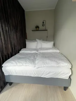 a bed with white sheets and pillows in a bedroom at Modern apartment ONLY 5 minutes from City Centre in Bergen