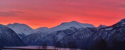a snow covered mountain range with a red sky at Villa Skoglund in Stranda
