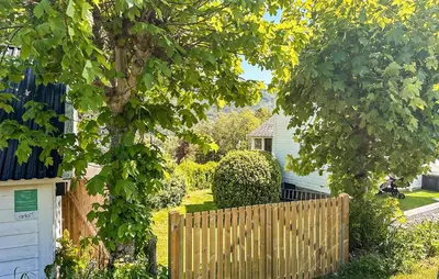 a wooden fence in front of a yard with a tree at 3 Bedroom Stunning Home In Vikebygd in Vikebygd