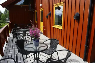 a patio with tables and chairs and flowers on a building at Camp Sjusjøen in Mesnali