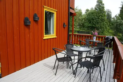 a patio with chairs and tables on a red wall at Camp Sjusjøen in Mesnali