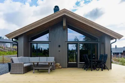a cabin with a couch and a table and chairs at New cabin at Skeikampen, perfect for families! in Svingvoll