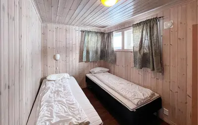 two beds in a room with wooden walls and a window at Gorgeous Home In Venabygd With Sauna in Venabygd