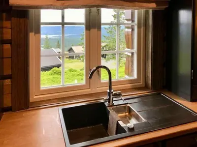 a kitchen sink and a window with a view at New log cabin with sauna, waxing shed & bench at Sjusjøen in Ringsaker