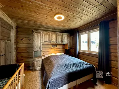 a bedroom with a bed in a wooden cabin at New log cabin with sauna, waxing shed & bench at Sjusjøen in Ringsaker