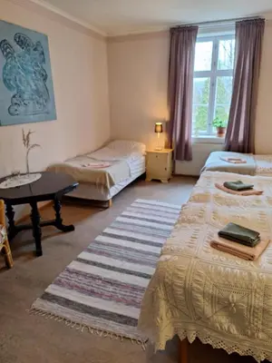 a bedroom with two beds and a table and a rug at Hurdal Gjestegård in Hurdal