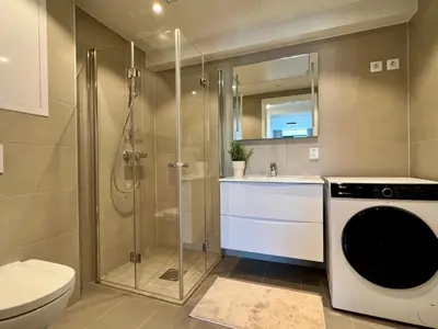 a bathroom with a shower and a washing machine at Høyegaarden in Bergen