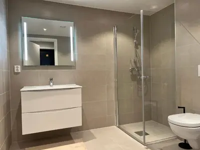 a bathroom with a shower and a toilet and a sink at Høyegaarden in Bergen