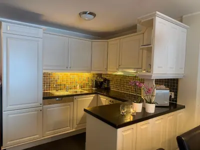 a kitchen with white cabinets and a black counter top at Enjoy Comfort Wi-Fi, Sauna & More! in Beitostøl