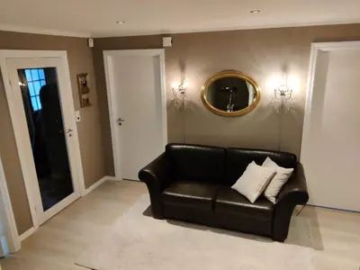 a black leather couch in a living room with a mirror at Nearby Bergen, Midtunlia 27d in Bergen