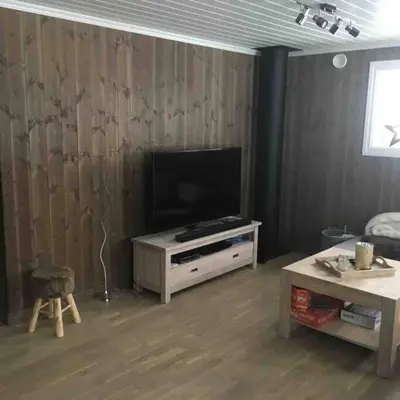 a living room with a flat screen tv and a table at Hytte med god standard in Stranda