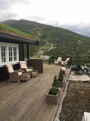 a wooden deck with chairs and trees on a house at Hytte med god standard in Stranda
