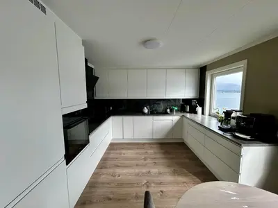 a large kitchen with white cabinets and a window at Magnar in Etnesjøen