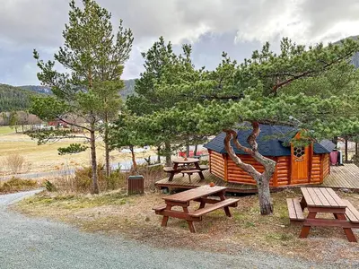 a group of benches and picnic tables in front of a cabin at 4 person holiday home in Lysøysundet in Teksdal