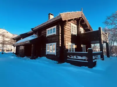 a log cabin in the snow with a bench in front at Geilo centrum - cozy apartment - central location in Geilo