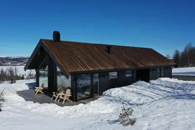 a cabin in the snow with two chairs in it at Golsfjellet - new modern cabin with fantastic view in Golsfjellet