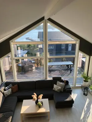 a living room with a couch and a large window at Seaside cottage with hot tub and sauna sleeps 11 in Forland