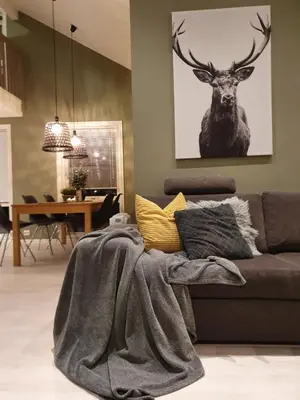 a living room with a couch with a deer picture on the wall at Seaside cottage with hot tub and sauna sleeps 11 in Forland