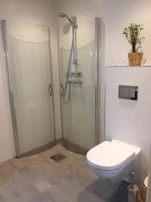 a bathroom with a shower and a toilet at Seaside cottage with hot tub and sauna sleeps 11 in Forland