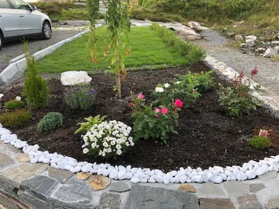 a garden with flowers and rocks in a yard at Seaside cottage with hot tub and sauna sleeps 11 in Forland