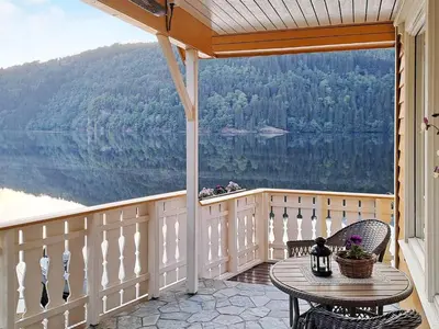 a balcony with a table and chairs and a view of a lake at 6 person holiday home in Bygstad in Bygstad