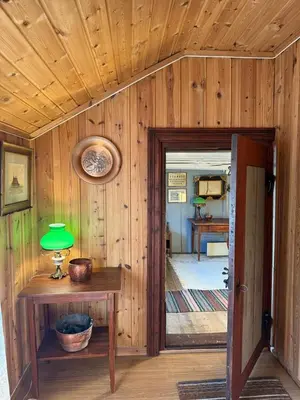 a room with a wooden wall with a table and a green lamp at Private pearl in downtown Røros in Røros