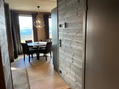 a dining room with a table and a door with a window at Riddertunets utsikt til Slettefjell in Beitostøl