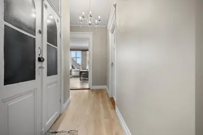 a hallway with a white door and a chandelier at Experience the luxury lifestyle 100m from Bryggen! in Bergen