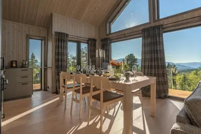 a dining room with a table and chairs and windows at Stryn Wiew Logde Tverrfjellet in Stryn