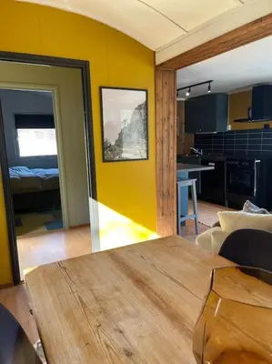 a living room with a table and a kitchen at Koselig gårdshus in To