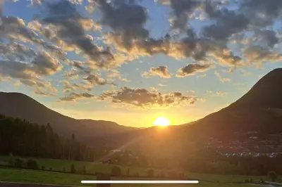 a sunset in the mountains with the sun in the sky at Koselig gårdshus in To